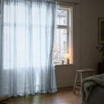 Gardin af organza i isblå foran et vindue